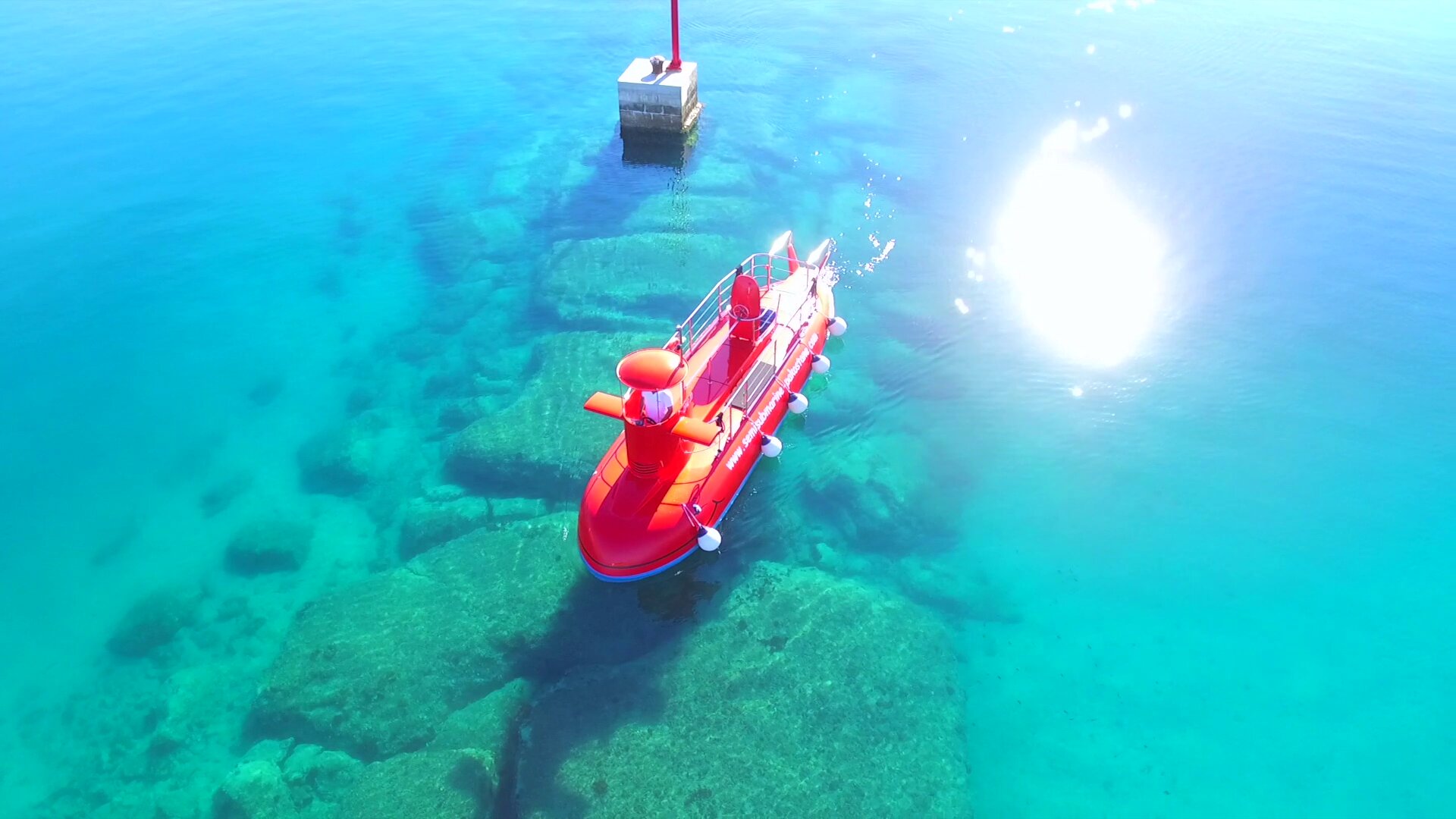 Red semi-submarine gliding over crystal-clear turquoise Adriatic shallows near Pakoštane